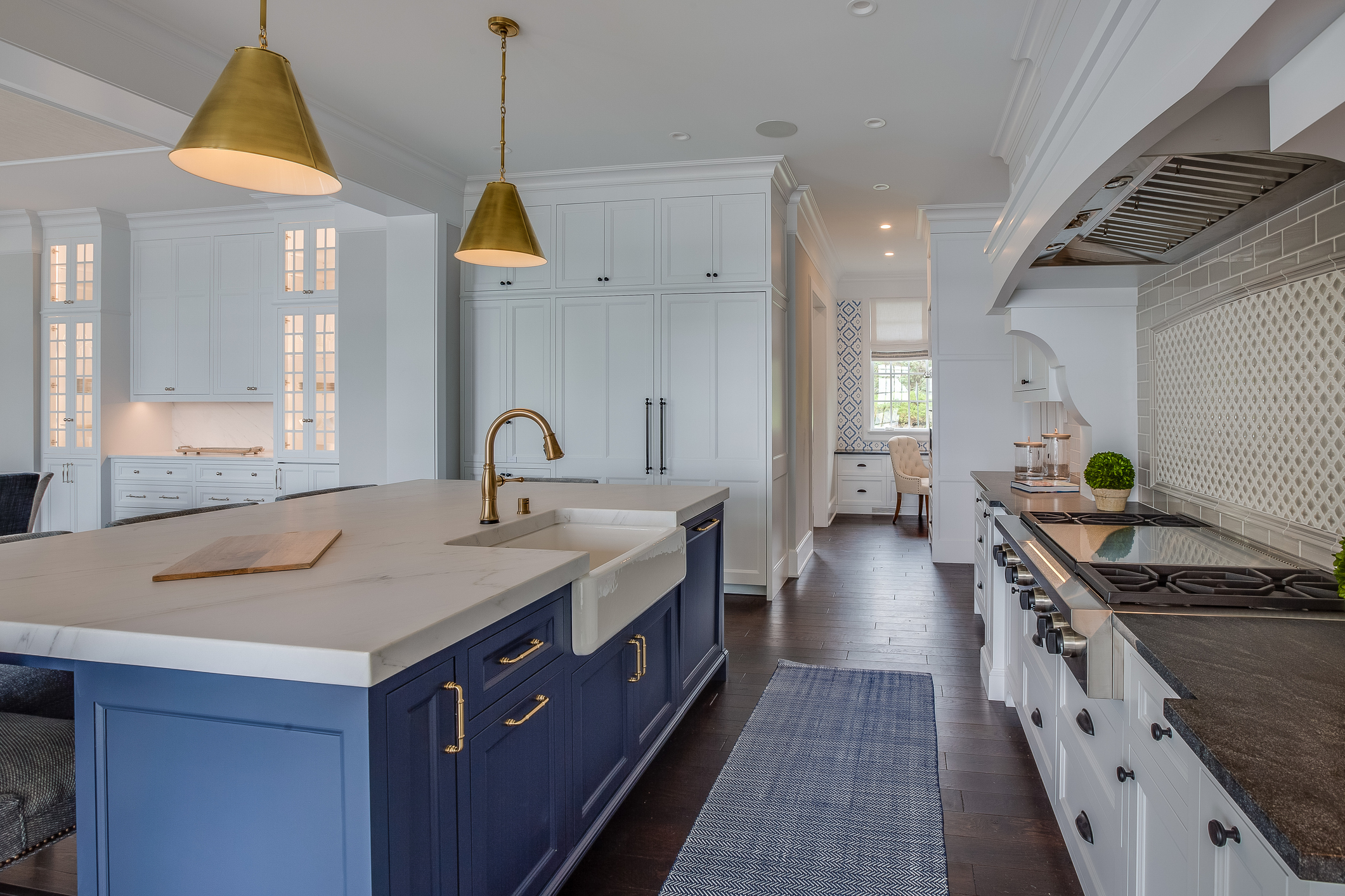 Kitchen galley with dark hardwood floors and blue rug to match island cabinets